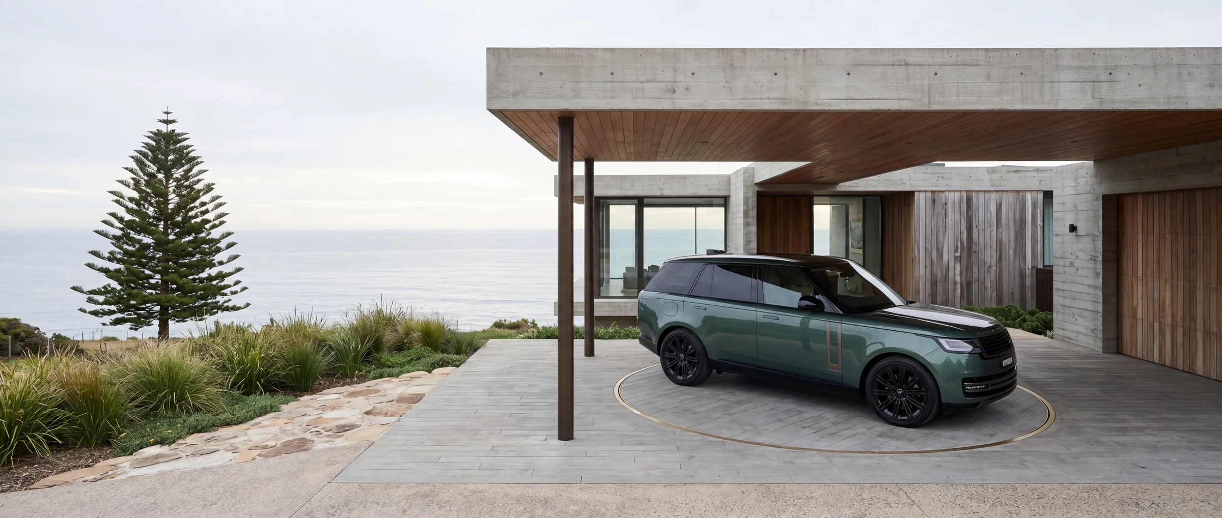Range Rover Autobiography in Belgravia Green on a turntable at an Australian coastal home, with the ocean and cliffside landscape beyond.